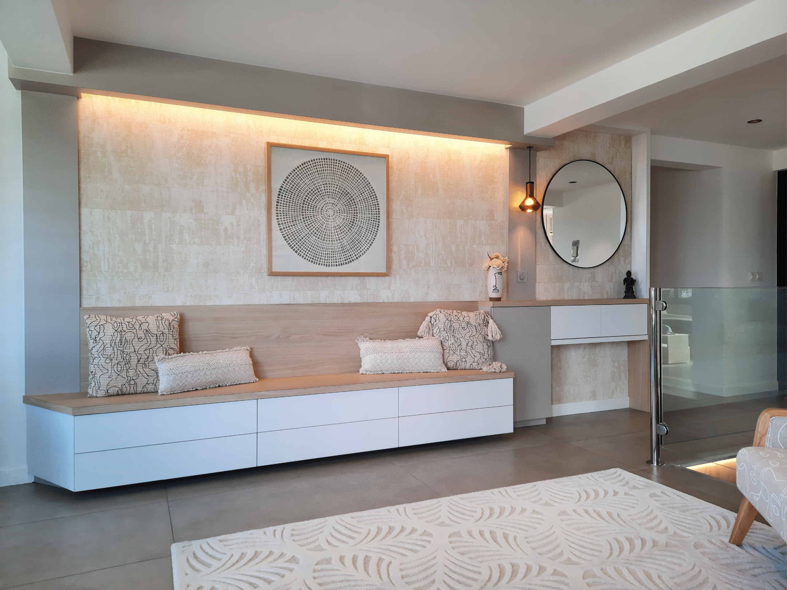 Espace détente contemporain avec banquette bois clair, mur texturé beige et éclairage indirect, réalisé par Grichka Interiors Design