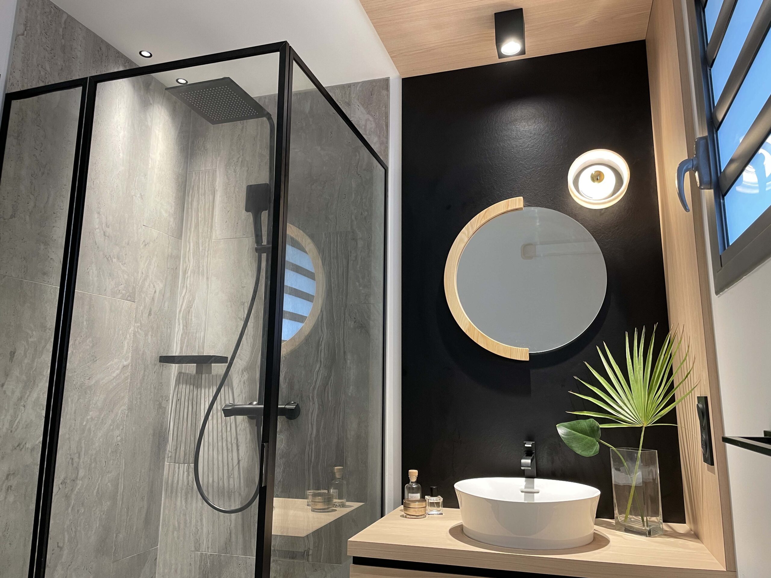 12 Décoration intérieure moderne avec table en bois, objets design noirs, orchidée blanche, mur texturé beige et miroir organique, réalisée par Grichka Interiors Design.