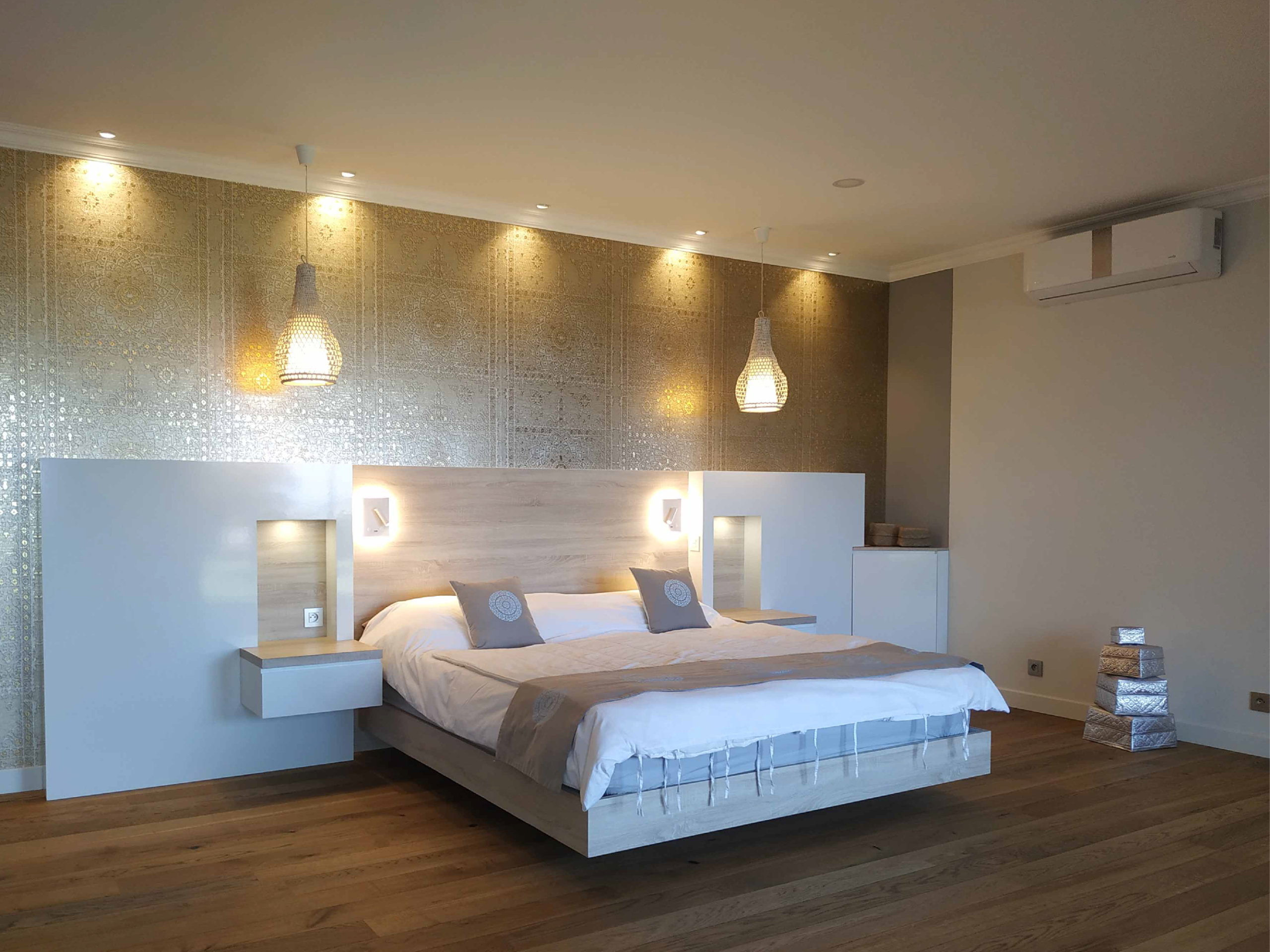 2 Chambre moderne avec tête de lit en bois clair, suspensions en rotin, murs dorés texturés et éclairage doux, réalisée par Grichka Interiors Design.